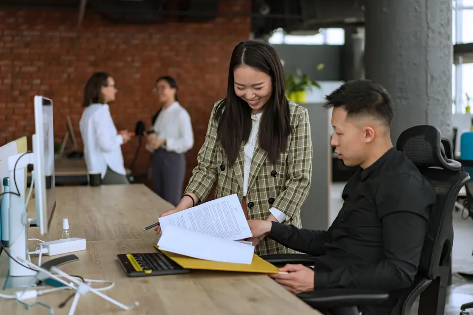 Dua orang bekerja di meja kantor dengan folder dan dokumen, foto ilustrasi