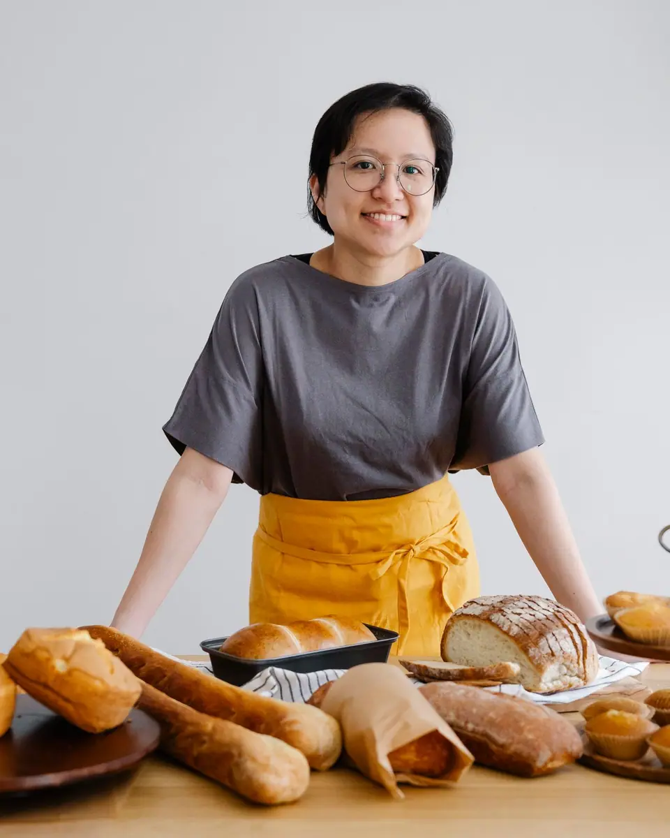 Pemilik toko roti berdiri di belakang meja berisi roti