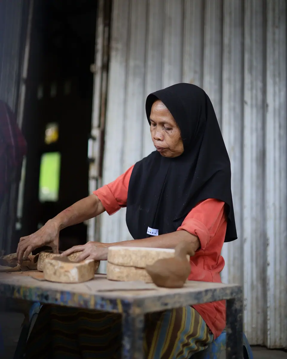 Perempuan berhijab membuat tahu di tempat usaha rumahan